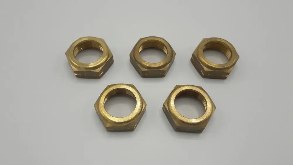 Fünf Verbindungsmuttern aus Messing, hergestellt von Remeha, in hexagonalem Design. Auf einem grauen Untergrund angeordnet.